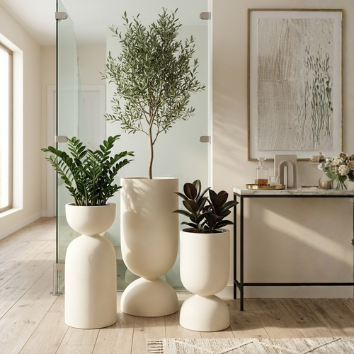 Modern interior with three potted plants in white hourglass shaped pots on a wooden floor.